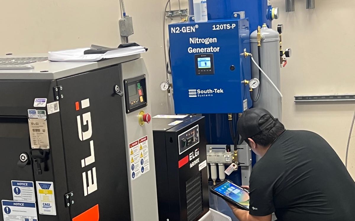Industrial service technician reviewing compressed air and nitrogen system data on a tablet